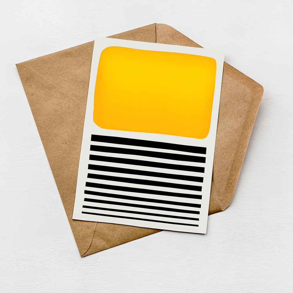 a card with a yellow square and black horizontal stripes, placed on top of a brown envelope.