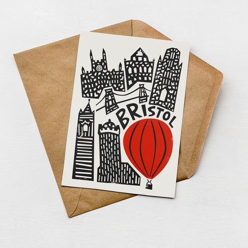 a card with a cityscape illustration and a red hot air balloon, along with the word "BRISTOL" written on it.