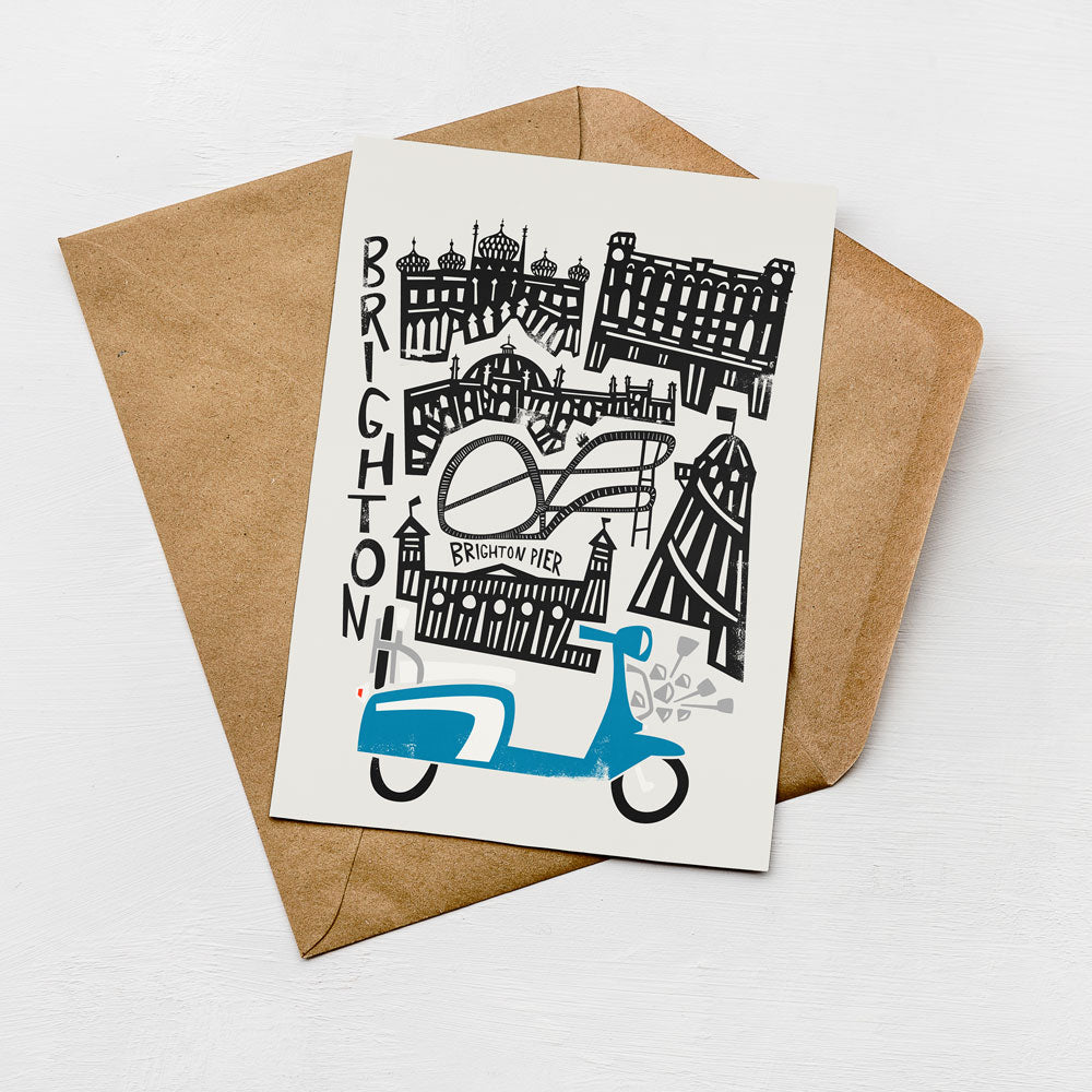 A card with a graphic design featuring various buildings and a blue scooter, placed on a brown envelope.