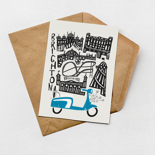 A card with a graphic design featuring various buildings and a blue scooter, placed on a brown envelope.