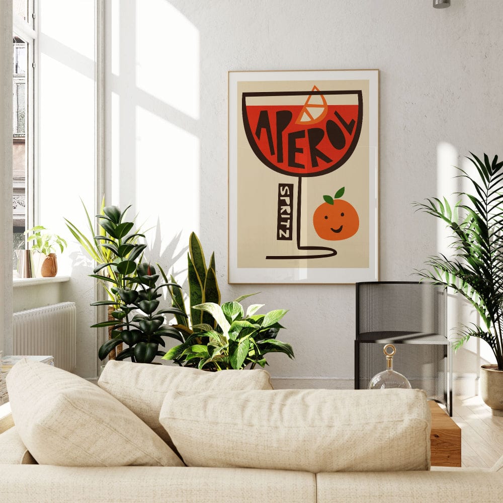 Aperol cocktail print styled in a sunlit modern lounge with leafy plants and cream furnishings.