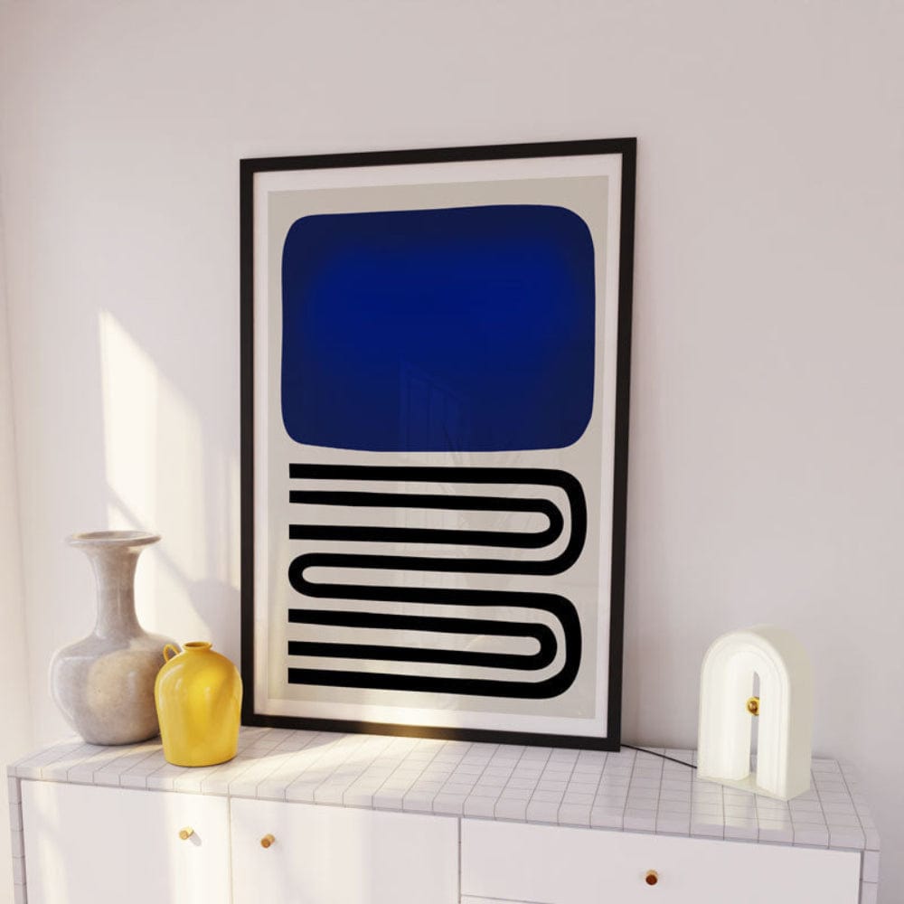 Blue and black abstract artwork framed above white sideboard with warm-toned vases
