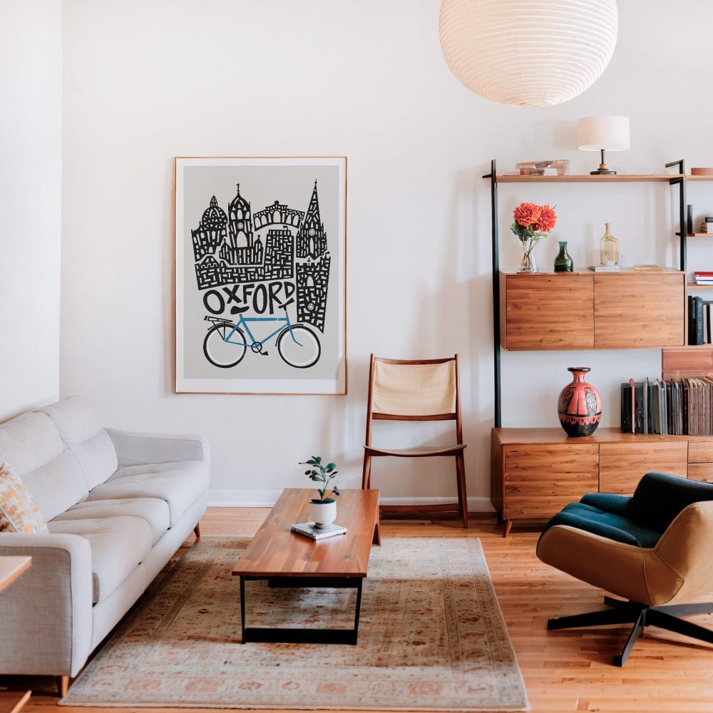 A framed Oxford print hanging in a modern lounge, the bold black architecture and soft blue bicycle offering contrast and sophistication to the curated space.
