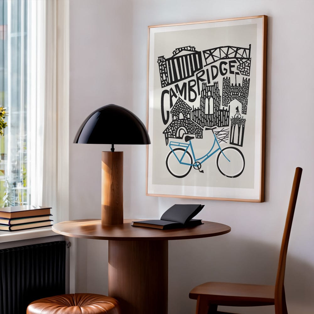 Framed Cambridge city illustration hung above a tidy writing desk, showcasing collegiate charm and vintage-inspired architecture in a clean modern setting.