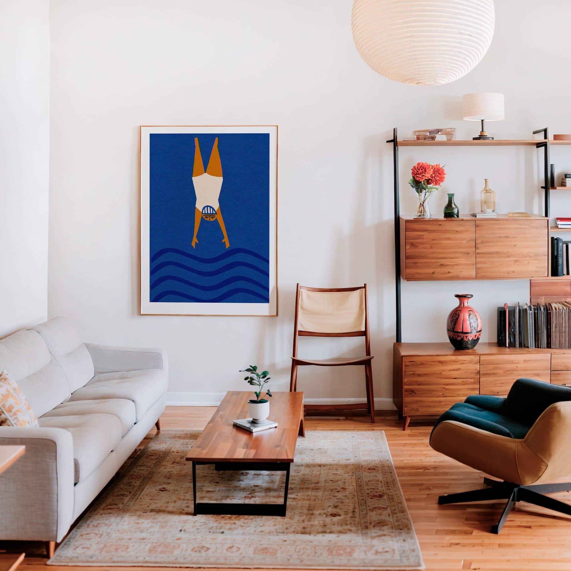 Framed diver art print styled above neutral sofa in warm-toned living space with modern shelving.