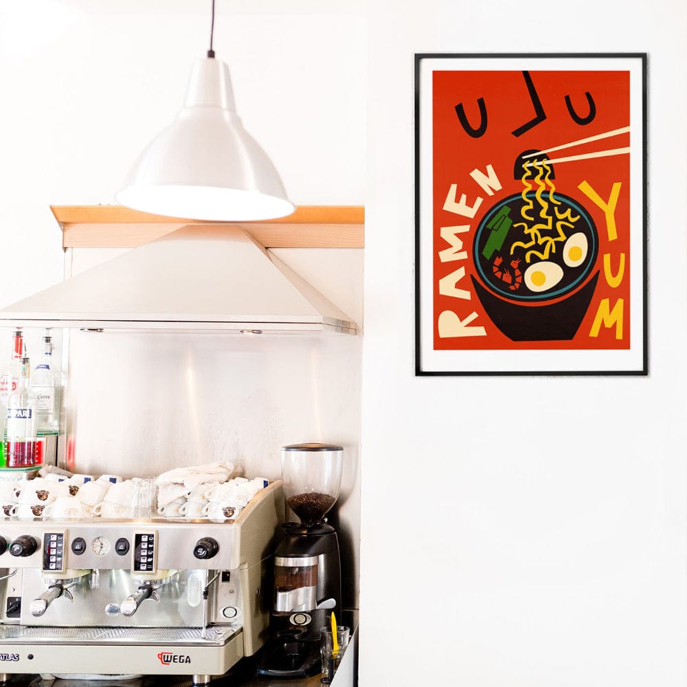Eye-catching ramen print displayed in a minimal café interior above a commercial espresso machine.