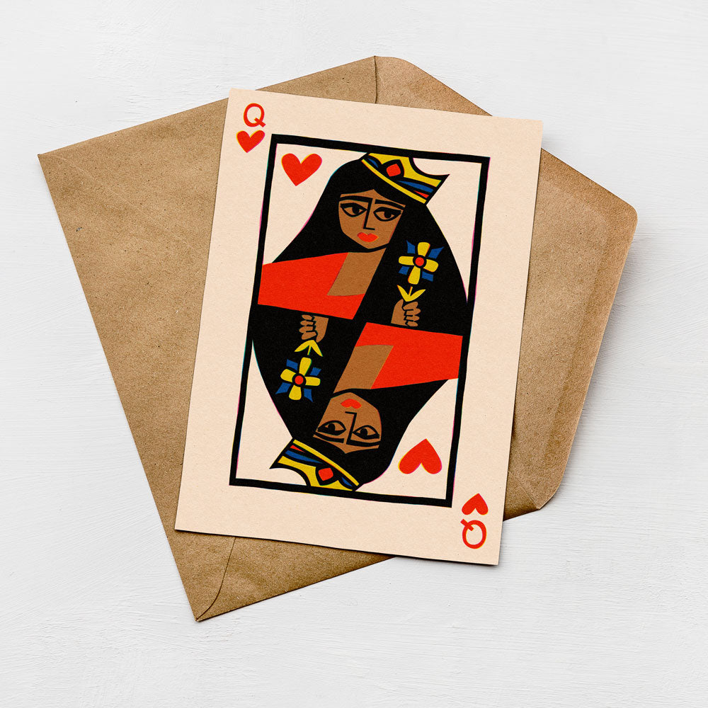 A greeting card featuring a stylized illustration of a queen of spades playing card with a red heart and a yellow flower on the left side.
