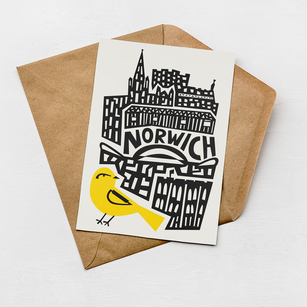 A card with a stylized illustration of a city skyline and a yellow bird on it, placed on a brown envelope.