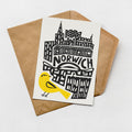 A card with a stylized illustration of a city skyline and a yellow bird on it, placed on a brown envelope.