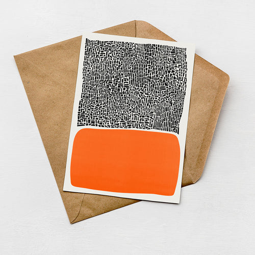 a piece of paper with a black and white abstract design and an orange rectangle on top of it, placed on a brown envelope.