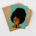 A card with a stylized illustration of a woman's face on a turquoise background, placed on top of a brown envelope.