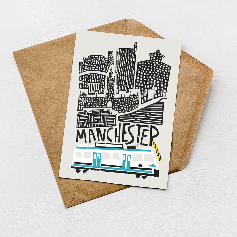 a card with a stylized illustration of a city skyline, including a train, and the word "MANCHESTER" written on it.