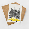A greeting card featuring a stylized illustration of a yellow taxi in front of a city skyline, with the text "NYC" prominently displayed.