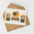 A greeting card with an illustration of a record player and two speakers, along with a brown envelope.
