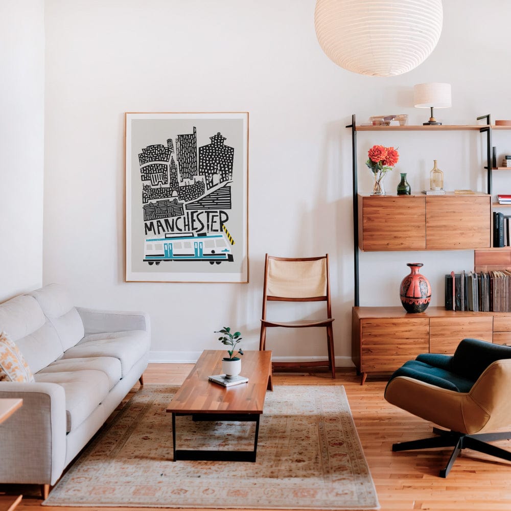 The Manchester city print displayed in a modern living room setting, its layered urban composition standing out against warm neutral interiors.