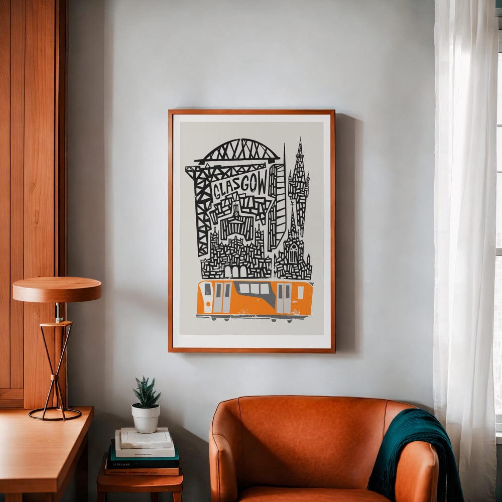 The Glasgow print hangs neatly on a grey wall above a rust-coloured chair and warm wooden side table, offering a bold yet balanced focal point with its punchy orange subway detail.
