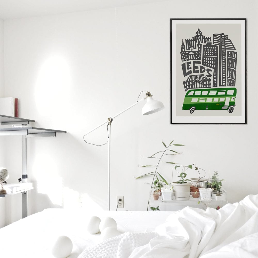 The Leeds city print hung in a minimalist white bedroom, its green and monochrome design adding a bold graphic edge to the soft neutral surroundings.
