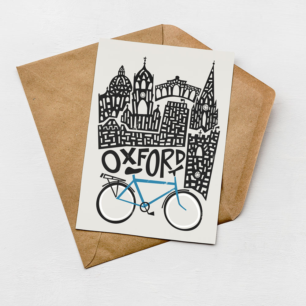 A card featuring a stylized illustration of a city skyline with a blue bicycle in the foreground, placed on top of an envelope.