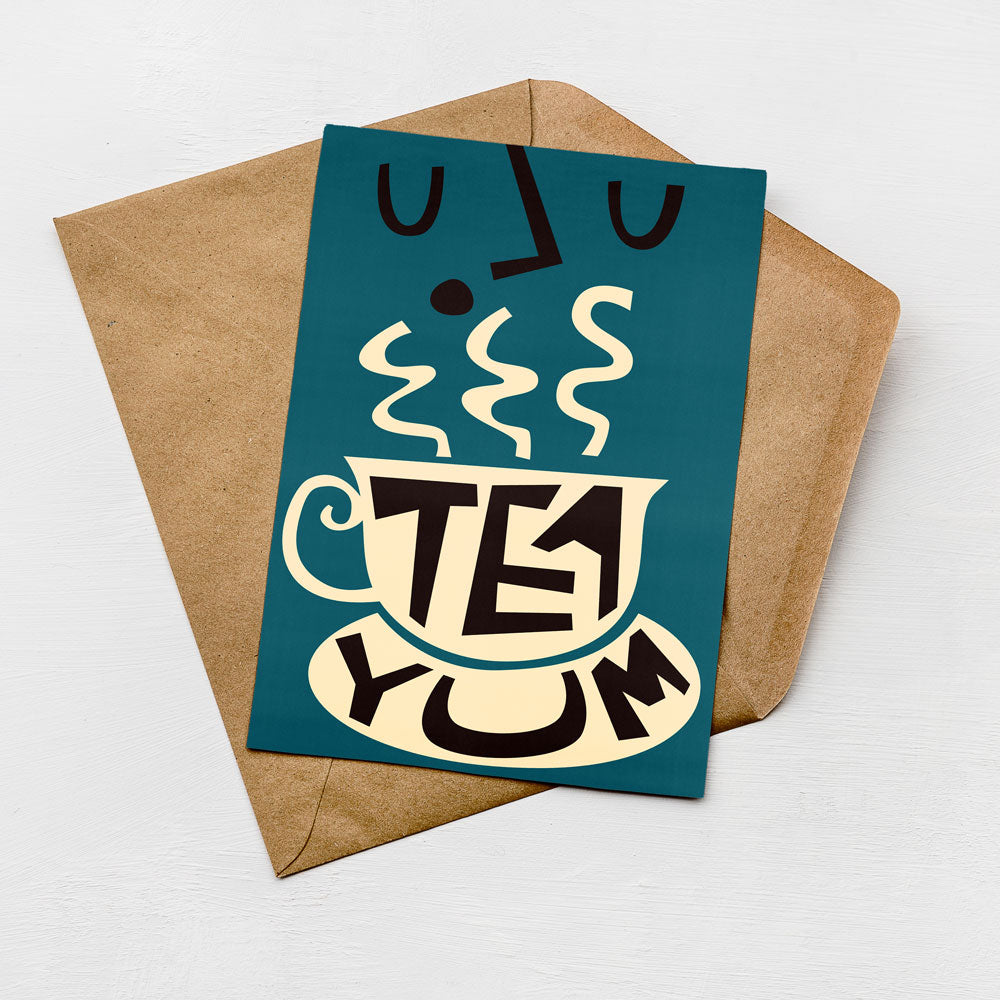 A greeting card with a teacup and steam design, accompanied by the text "TEE YUM" on the card.