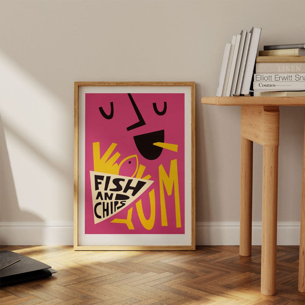 Vibrant food-themed art print propped against a wall beside a wooden desk, styled in a warm home interior.