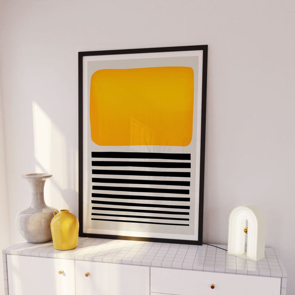 Yellow and black graphic art print framed above white sideboard with ceramic and glass decor