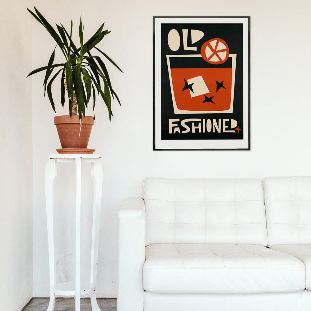 Old Fashioned cocktail poster framed above a white modern sofa with a tall houseplant for a fresh, graphic look.