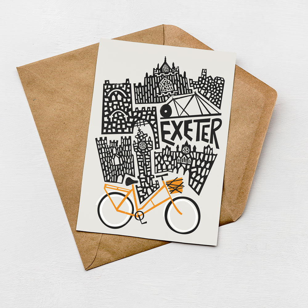 a card with a stylized illustration of a cityscape, including a bicycle, and the word "Exeter" prominently displayed.