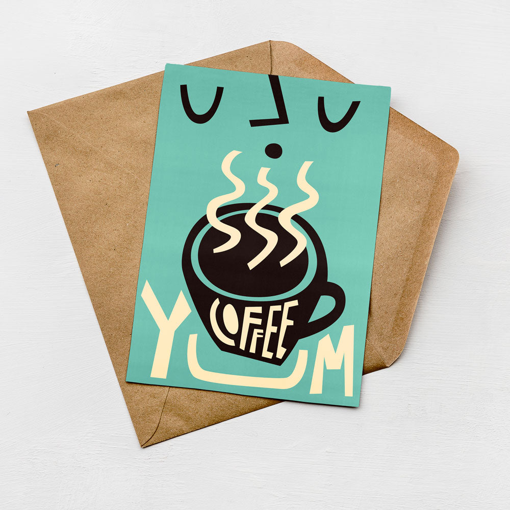 A card with a stylized coffee cup design and the text "COFFEE YUM" printed on it, placed on top of an envelope.