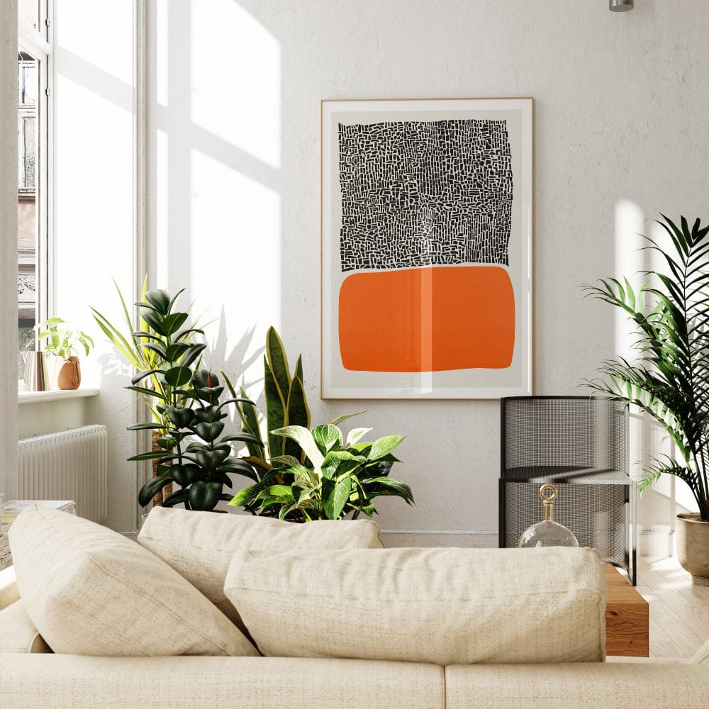The orange block print hanging in a sun-filled living room with light-toned furnishings and indoor plants, giving the space an inviting, modernist atmosphere.