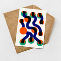 a card with a colorful abstract design on it, placed on top of a brown envelope.