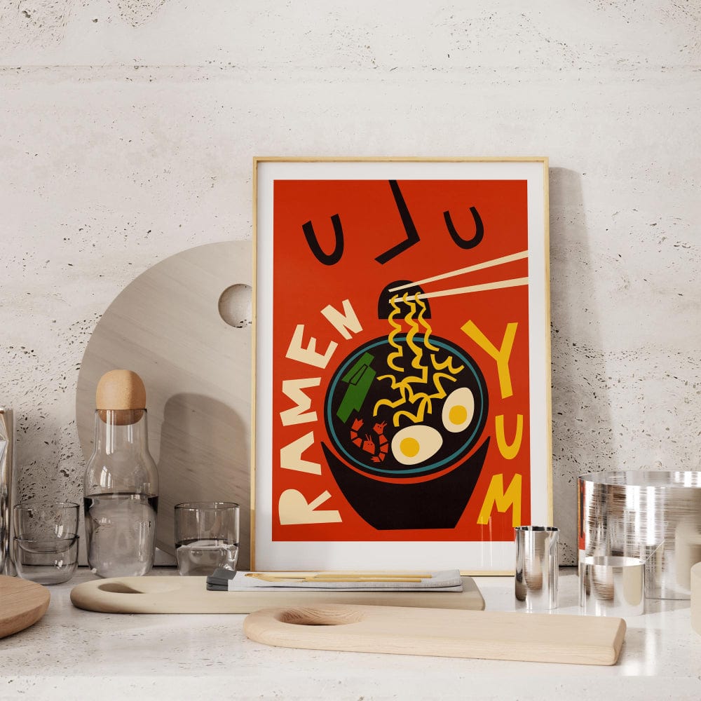 The Ramen Yum poster casually leaned on a modern white kitchen shelf with neutral ceramics around it.
