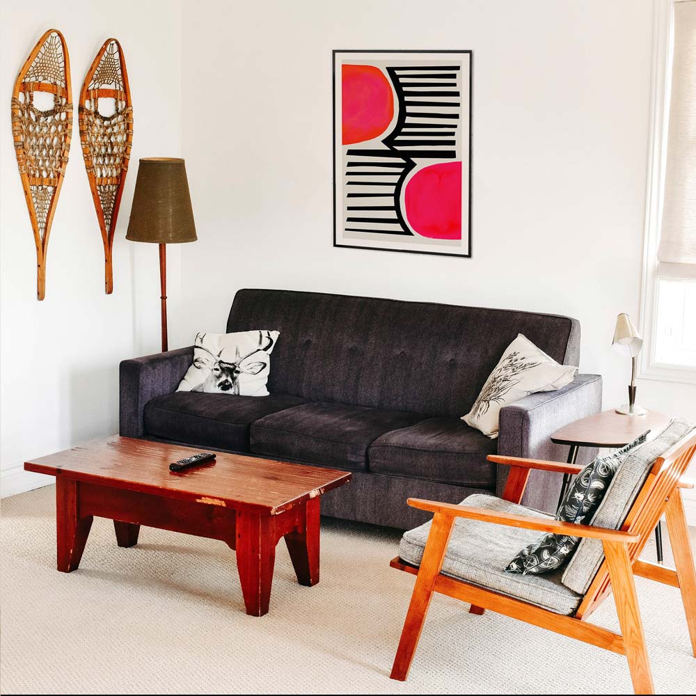 Geometric abstract print adding a bold splash of pink and black to a mid-century inspired living space.