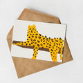 A greeting card featuring a stylized illustration of a leopard or cheetah on a white background, with a brown envelope underneath.
