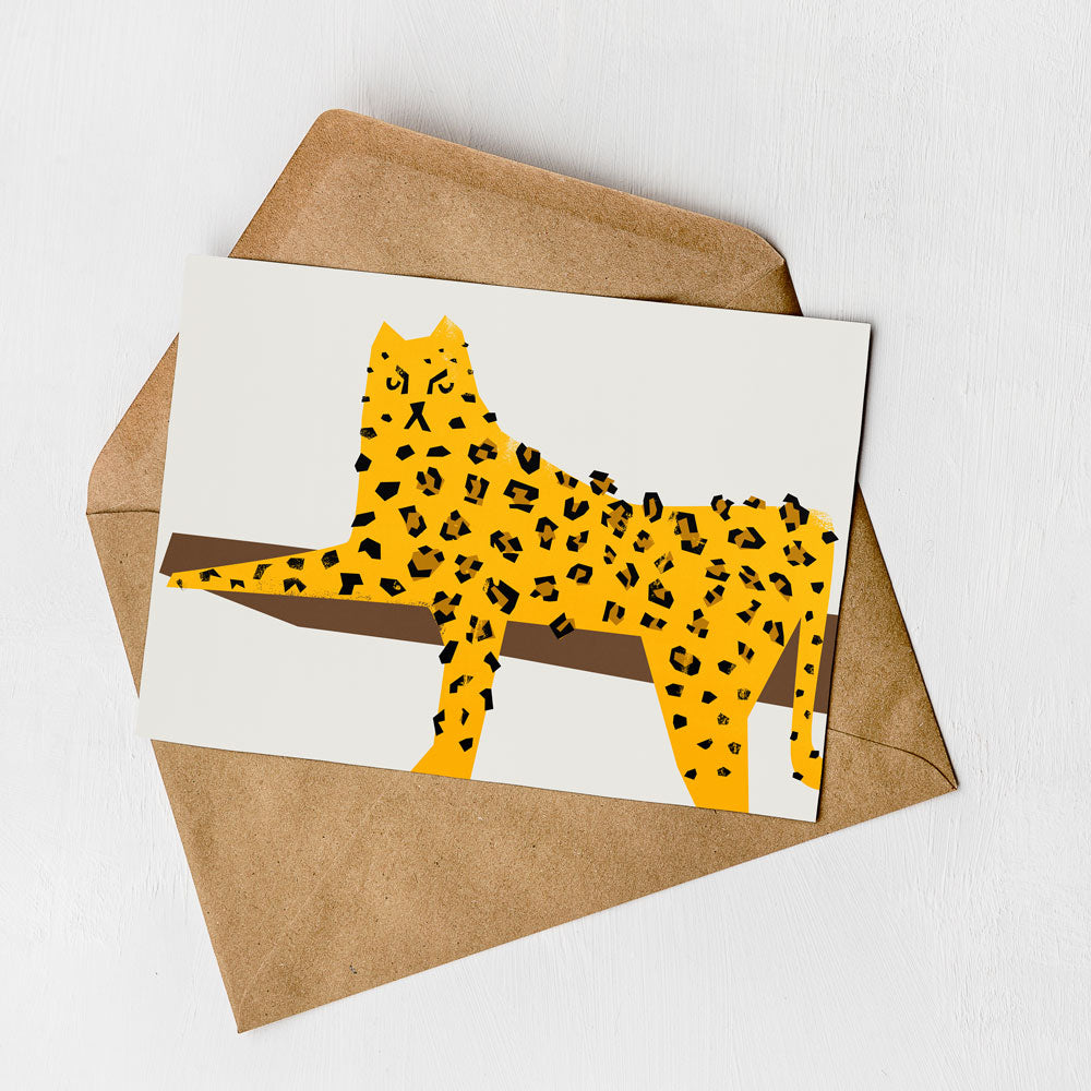 A greeting card featuring a stylized illustration of a leopard or cheetah on a white background, with a brown envelope underneath.
