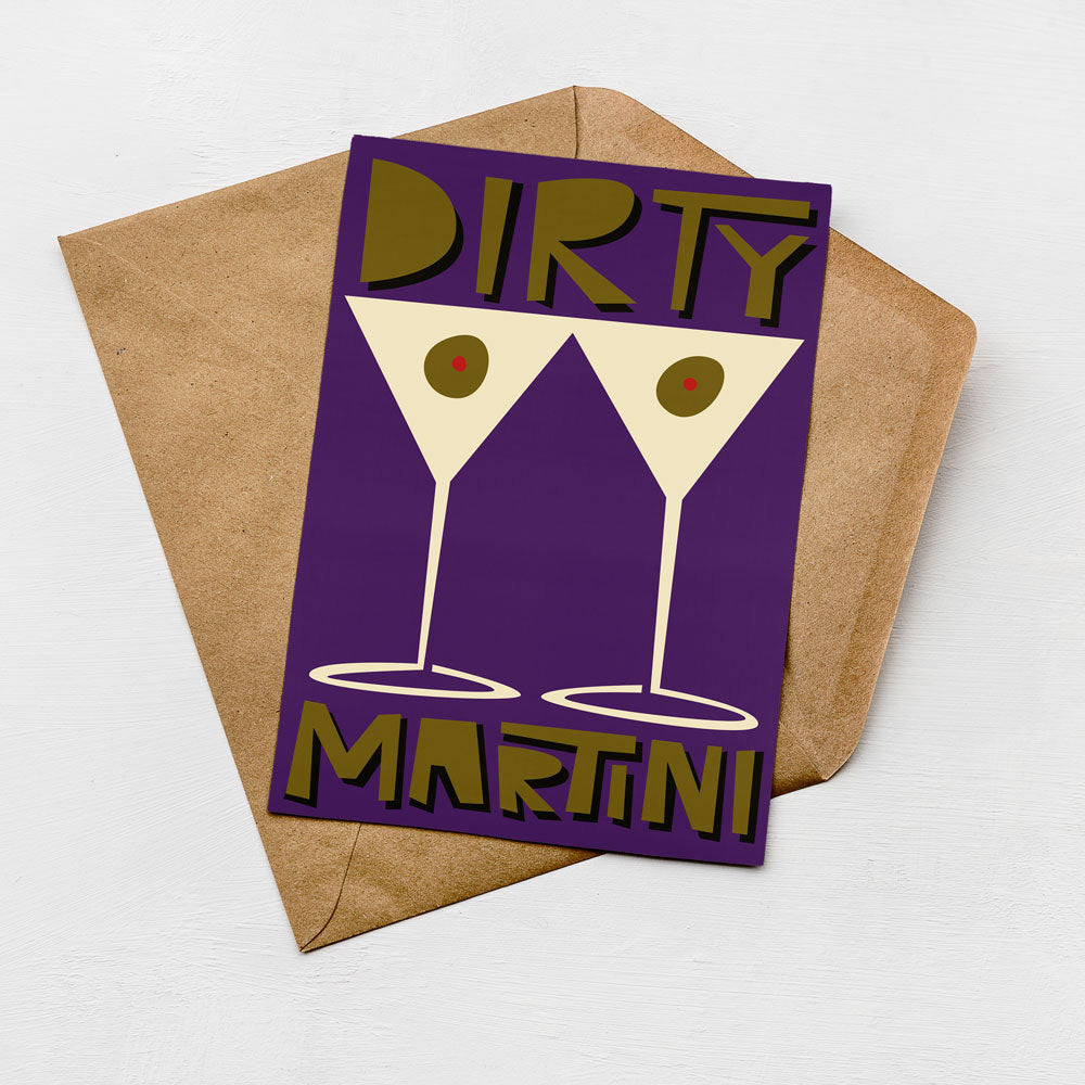 A purple card with a graphic design featuring two martini glasses and the text "Dirty Martini" on it, placed on a brown envelope against a white background.