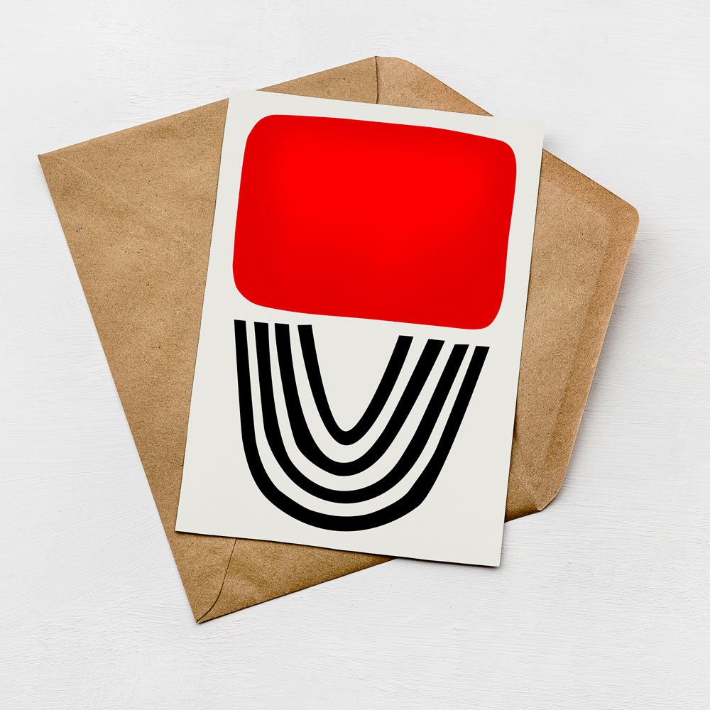a white card with a red square and black lines on it, placed on top of a brown envelope.