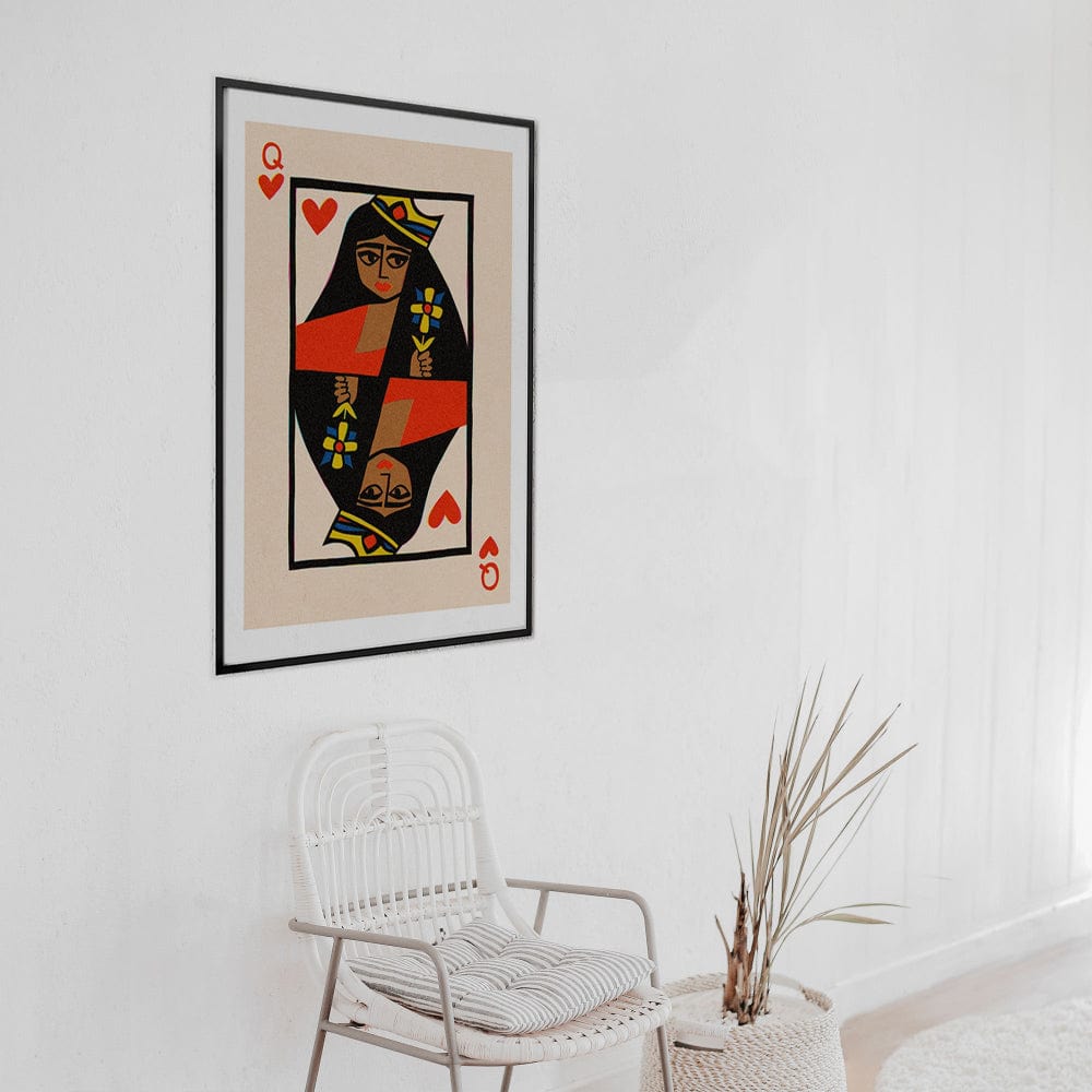 Queen of Hearts print framed on clean white wall with natural chair and dried botanical styling