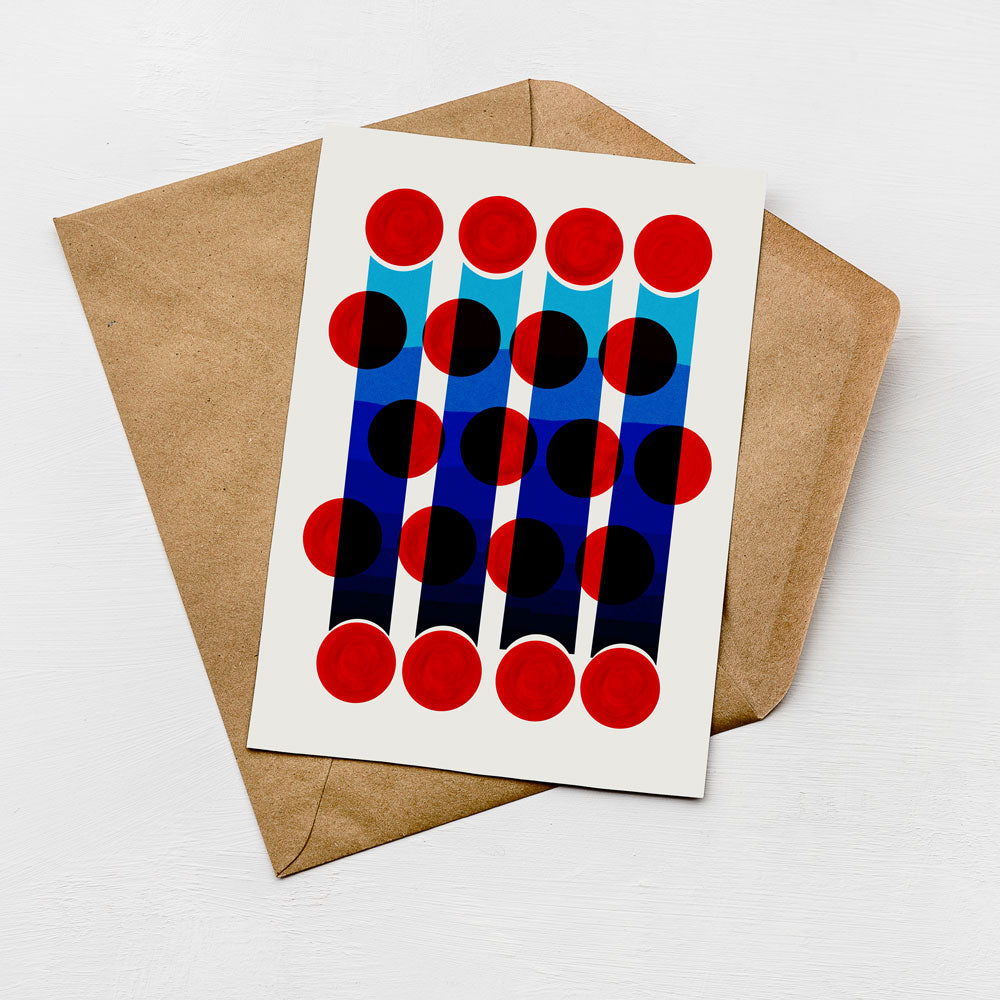 a white card with a geometric design of red and blue circles on it, placed on top of a brown envelope.