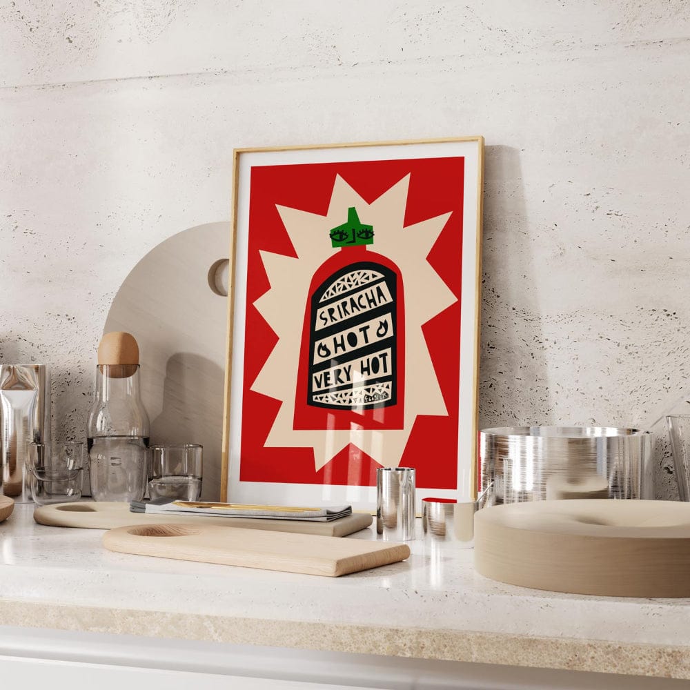 Sriracha print framed on a stone-textured kitchen shelf with glassware and utensils.