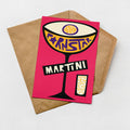 A colorful illustration of a martini glass with the word "MARTINI" written on it, placed on a brown envelope against a white background.